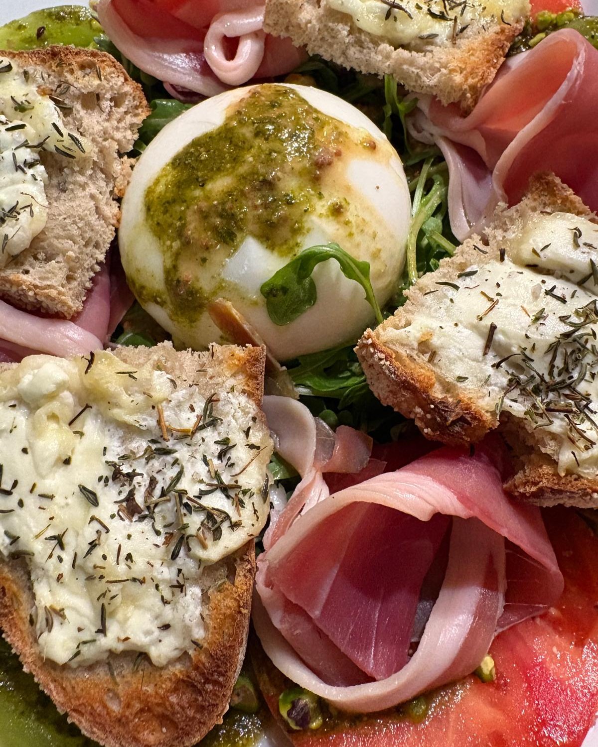 Burrata salad: burrata with pesto, cured ham, rocket, tomatoes and warm goat's cheese toasts
